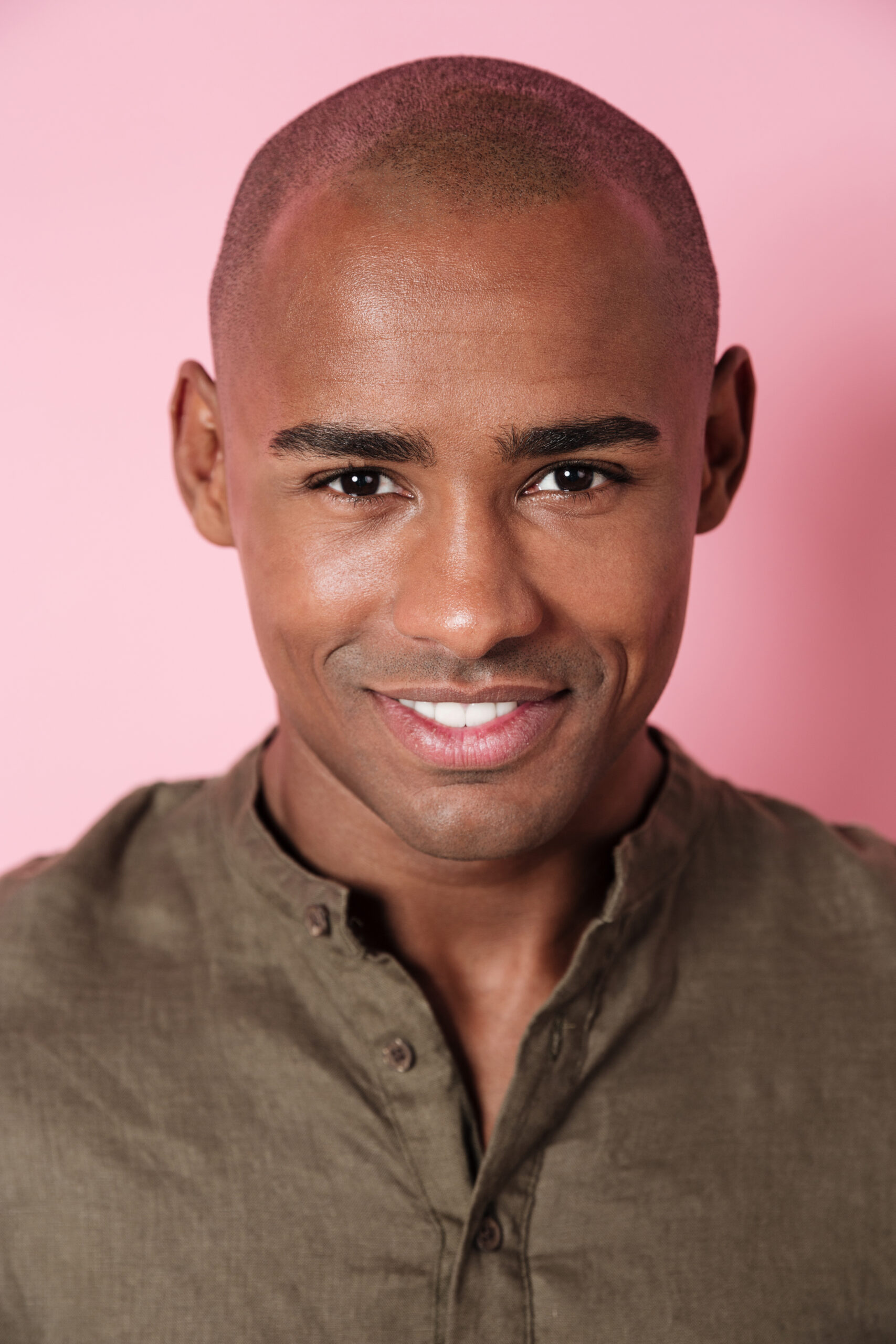 Close up vertical image of smiling african man looking at the camera over pink background